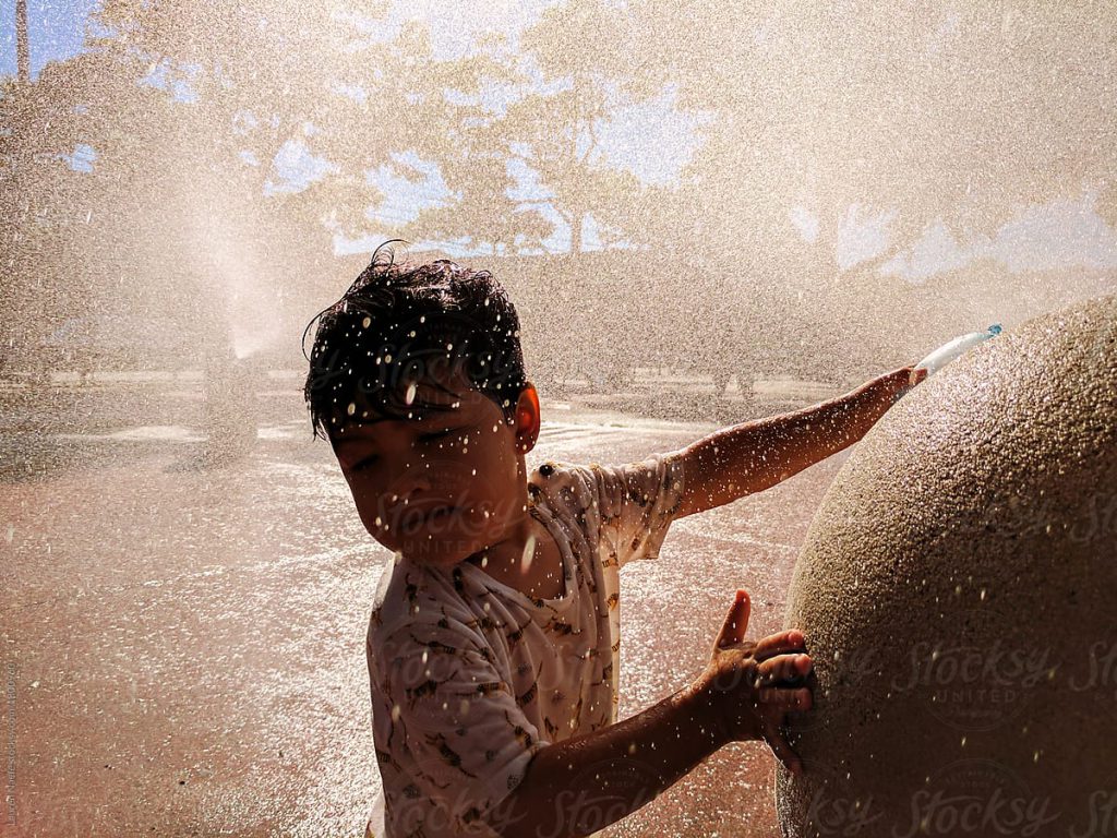 laughing child in sprinkling water in park